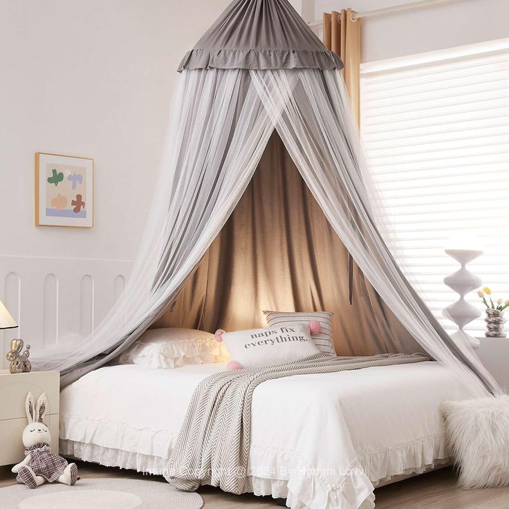 a white bed with a canopy over it in a bedroom next to a dresser and window