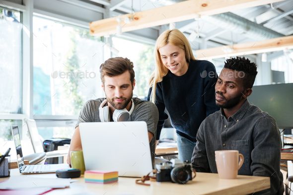 three people looking at a laptop screen in an office setting - stock photo - images