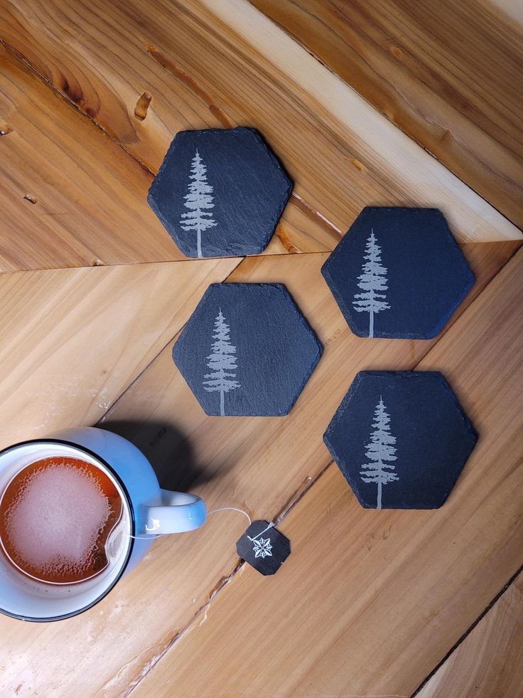 a cup of coffee sitting on top of a wooden table next to three coasters