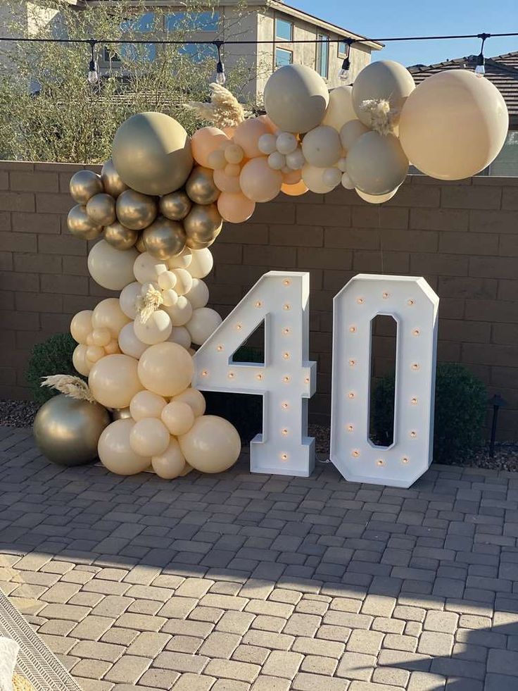 the number forty sign is made out of balloons and golds, white and silver