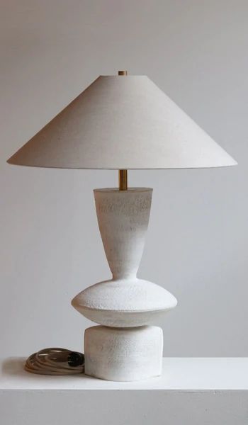 a white lamp sitting on top of a table next to a stack of coins and a coin