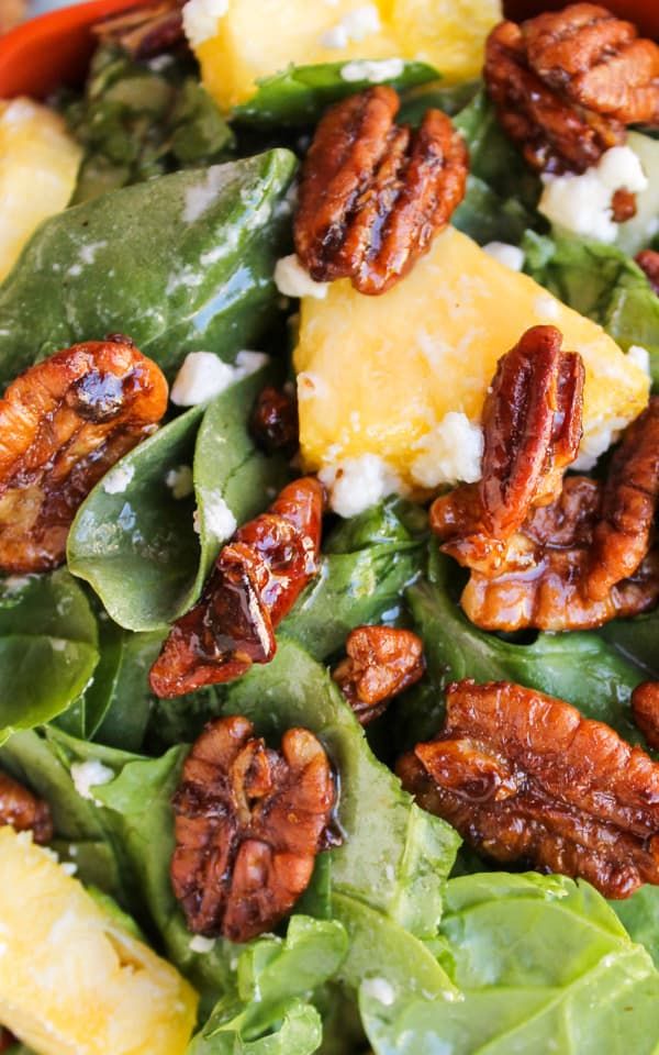 a salad with spinach, pineapples and pecans