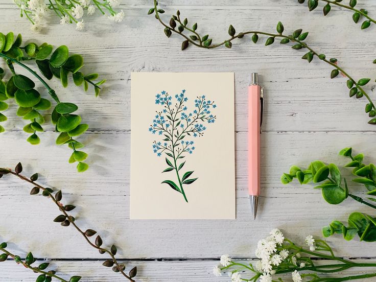 a notepad sitting on top of a wooden table next to flowers and a pen