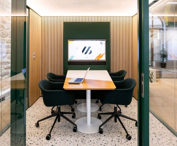 a table with two chairs and a laptop on it in the middle of a room