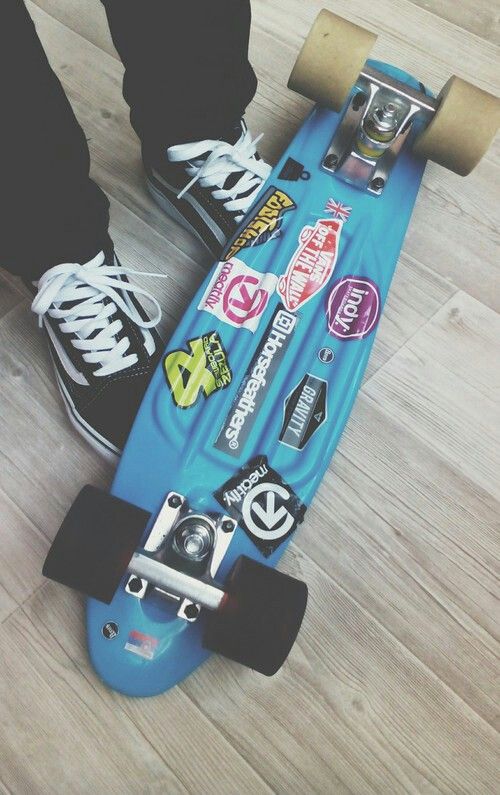 a person standing on top of a skateboard with stickers all over the board