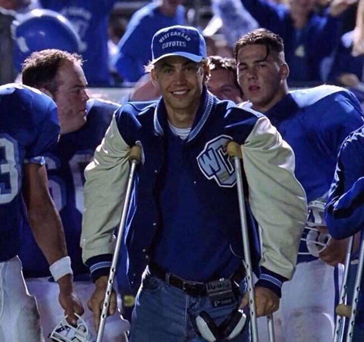 a group of men standing next to each other on top of a football field wearing blue and white uniforms