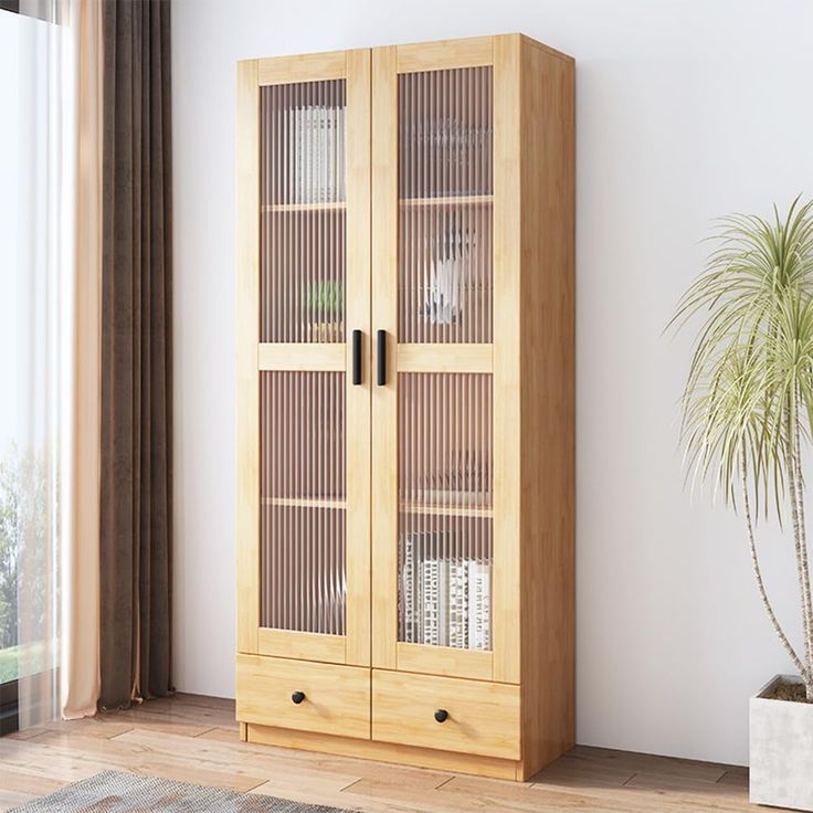 a tall wooden cabinet with glass doors next to a potted plant and window sill