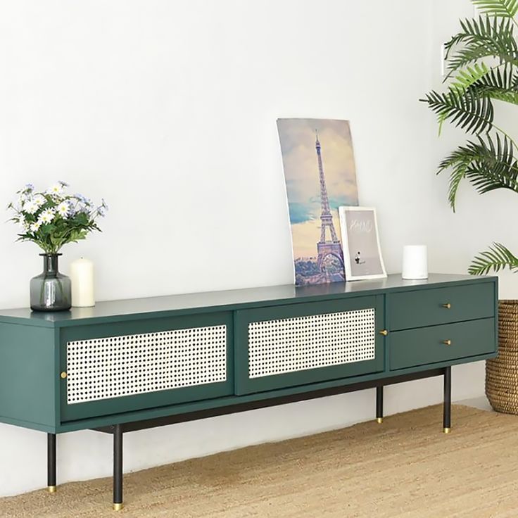 the sideboard is painted green and has gold trimmings on it, along with some plants