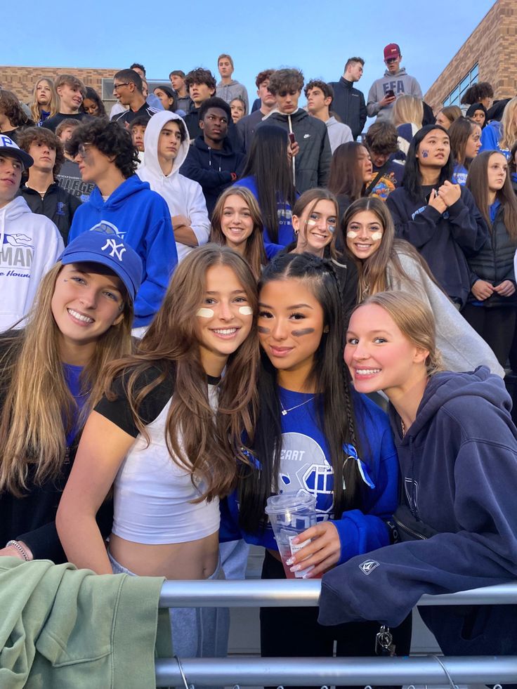 a group of young women standing next to each other in front of a crowd of people