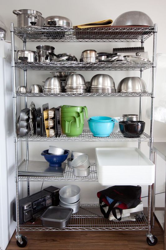 a kitchen shelving unit with various pots and pans on the shelves, including an oven