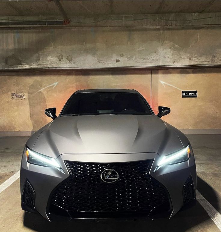 the front end of a silver sports car in a parking garage with no one around