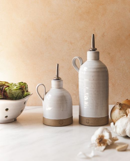 three ceramic containers sitting on top of a counter next to garlic and other food items