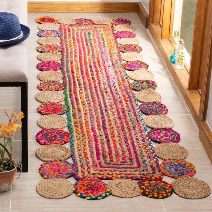 a colorful rug is on the floor next to a vase with flowers and other items