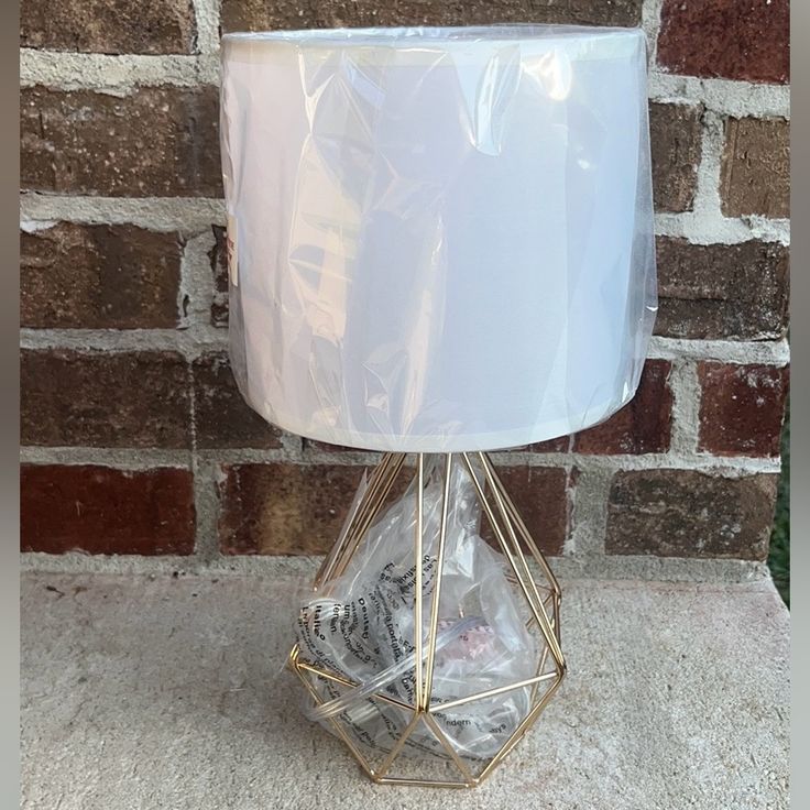 a lamp that is sitting on top of a stone floor next to a brick wall