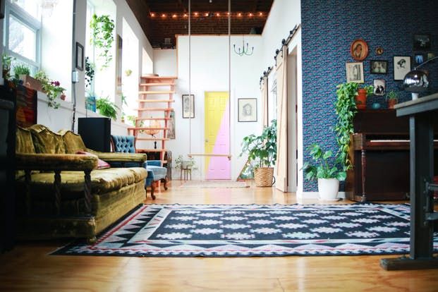 a living room filled with furniture and lots of plants on top of the rugs