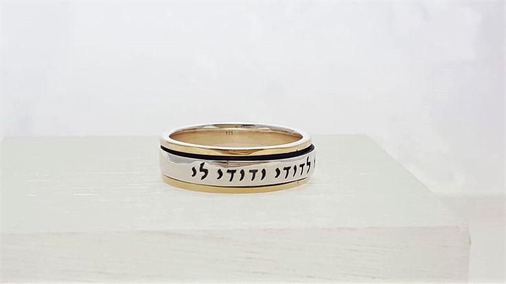 "\"Ani L'Dodi V'Dodi Li BAND ROLLING RING\" This beautiful rolling band ring is made of 925 Sterling Silver and 9 kt gold. ( Marked 925 and 9K) Size: 6, 7, 8, 9, 10,11 Engraved in Hebrew letters: \"Ani L'Dodi V'Dodi Li\" \"I am my beloved's and my beloved is mine,\" - Song of Songs (Shir HaShirim), Chapter 6, verse 3A. Many phrases from The Song of Songs written by King Solomon, have been used throughout weddings for centuries. When you read the entire poem from where this phrase comes from, it Spiritual Engraved Wedding Ring, Handmade Gold Stackable Rings For Wedding, Handmade Yellow Gold Stackable Wedding Rings, Adjustable Engraved Wedding Rings, Heirloom Wedding Rings With Adjustable Fit, Heirloom Wedding Rings Adjustable Fit, Spiritual White Gold Wedding Rings, Spiritual White Gold Rings For Wedding, Heirloom Style Engraved Adjustable Ring For Wedding