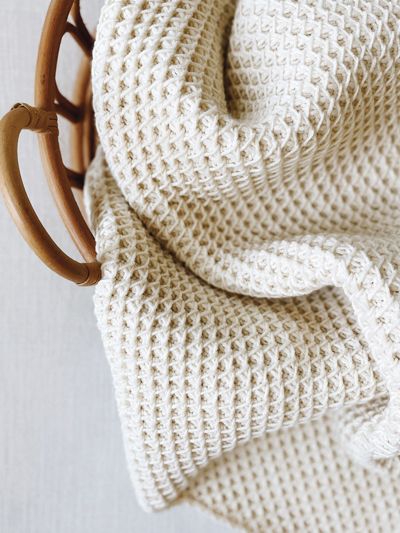 a white knitted blanket hanging from a wooden hanger