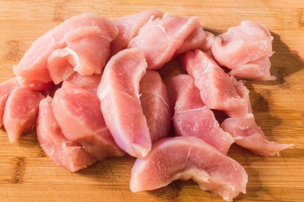 pieces of raw meat sitting on top of a wooden cutting board