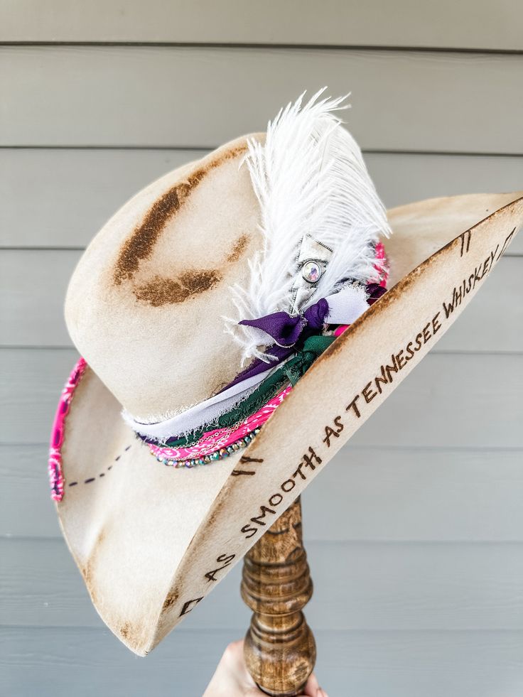 Silverbelly Hand Decorated Wool Cowgirl Hat Additional Information: Will need Head Measurement for hat All feathers and ribbons are glued to hold on to the hat. All hats are decorated, burned, hand-burned/engraved by Annrita Velardi Hat was burned, will have a slight odor at first. Please message us if you would like your hat personalized or have any questions. Branded Cowboy Hats, Artisan Hat Bands For Kentucky Derby Festival, Bohemian Festival Hat Bands With Feather Trim, Artisan Hat Bands For Kentucky Derby, Bohemian Hats With Feather Trim For Rodeo, Artisan Hats With Feathers And Adjustable Fit, Bohemian Rodeo Hat With Feather Trim, Bohemian Hat Bands With Feather Trim And Flat Brim, Bohemian Hat Bands With Feather Trim