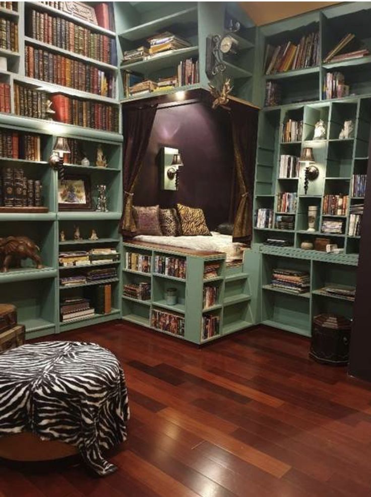 a room filled with lots of green bookshelves next to a couch and ottoman