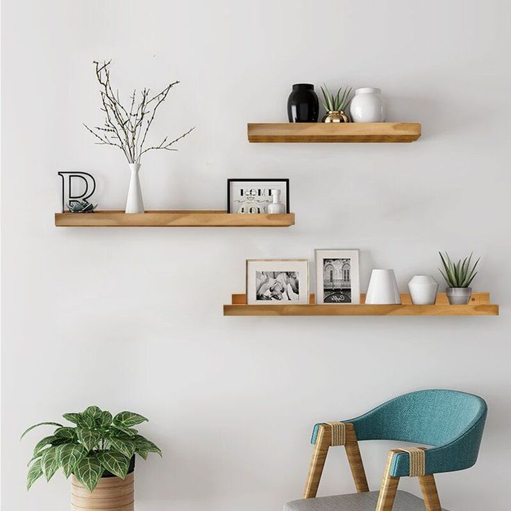 two wooden shelves on the wall above a chair and potted plant in a vase