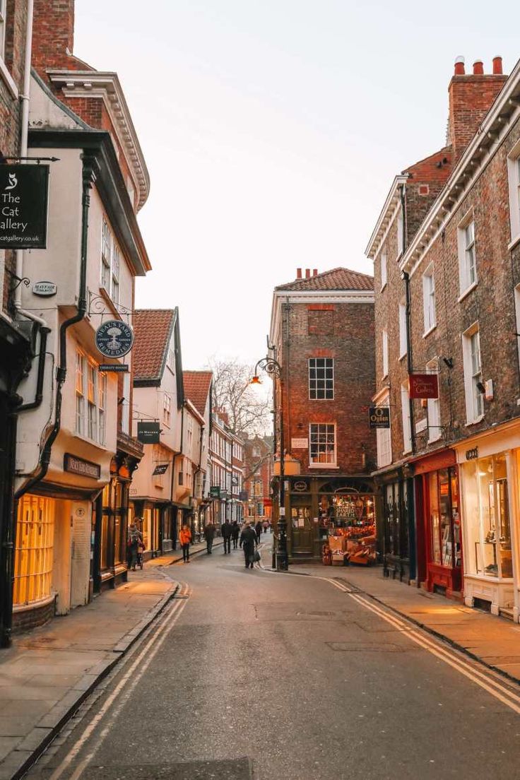 an empty street with people walking on the sidewalk and shops in the buildings around it