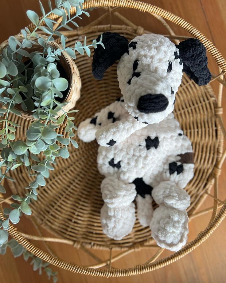 a crocheted dog sitting on top of a wicker basket next to a potted plant