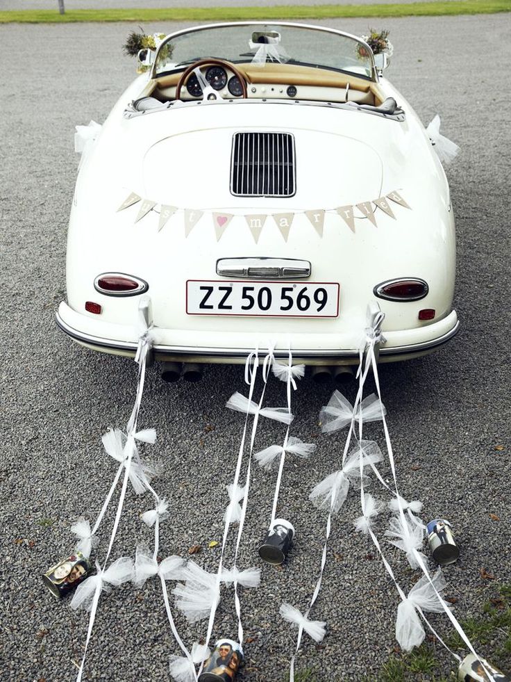 an old white car parked on top of a gravel road