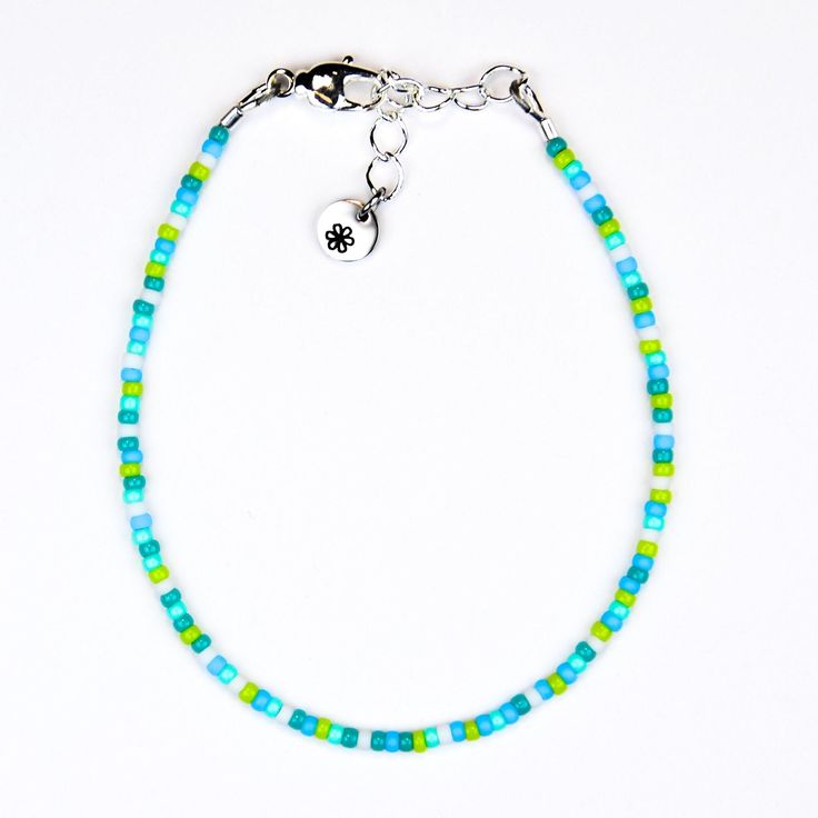 Add a touch of whimsy to any outfit with our Dainty bracelet. Featuring a playful mix of green, blue, and white seed beads, this bracelet is sure to turn heads and bring a smile to your face. Elevate your style with a touch of quirkiness! Materials:size 11/0 glass seed beadsbeading wiresilver plated crimp beadssilver plated wire guardssilver plated lobster claw claspsilver plated extension chainsilver plated logo charm Blue Heishi Beads Bracelet With Tiny Beads, Trendy Blue Bracelets With Tiny Beads, Trendy Blue Heishi Beads Bracelets, Trendy Blue Heishi Beads Jewelry, Trendy Blue Heishi Beaded Bracelets, Trendy Blue Beaded Bracelets With Tiny Beads, Trendy Blue Beaded Chain Bracelet, Blue Hand-strung Jewelry For Summer, Hand-strung Blue Jewelry For Summer