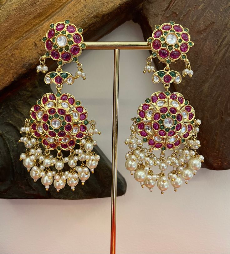 Look fabulous in these ruby red and green handcrafted earrings in kundan, accented with pearls to make you a show stopper.  Details: Earrings Length-4 Inches Earrings Width-1.5 Inches Weight of Each Earring-23 gms All products are manufactured using traditional skills from our rich heritage of crafts.  The process of these crafts is essentially manual. Hence, any irregularities or variations are an inherent part of these handcrafting processes. Traditional Red Pearl Earrings For Party, Festive Bollywood Ruby Chandbalis, Traditional Red Dangle Pearl Earrings, Bollywood Ruby Chandbali Bridal Earrings, Traditional Red Pearl Earrings For Wedding, Traditional Red Pearl Earrings, Temple Jewelry Ruby Earrings For Festive Occasions, Ruby Temple Jewelry Earrings For Festive Occasions, Red Pearl Earrings For Celebration