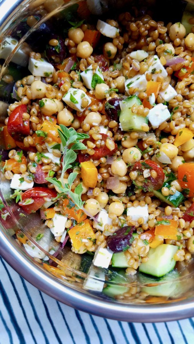 a metal bowl filled with lots of different types of food on top of a blue and white table cloth