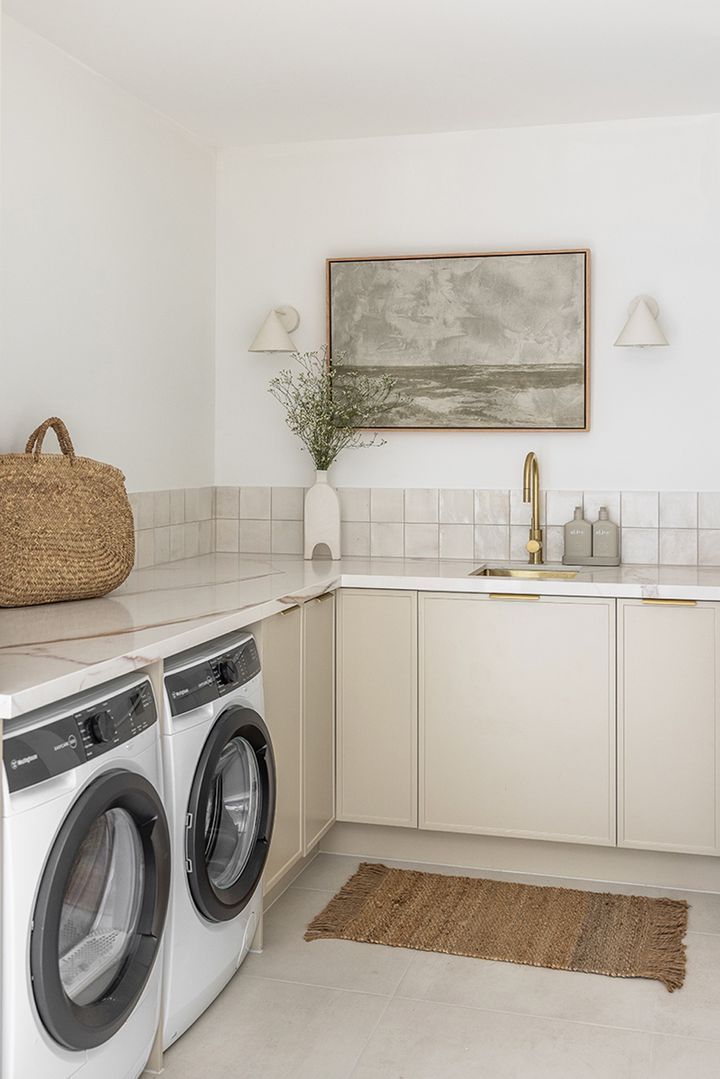 a washer and dryer sitting in a kitchen next to a counter with a basket on it