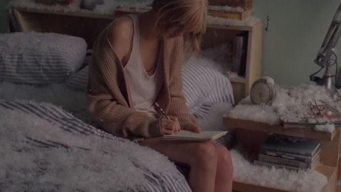 a woman sitting on top of a bed next to a book and pen in her hand