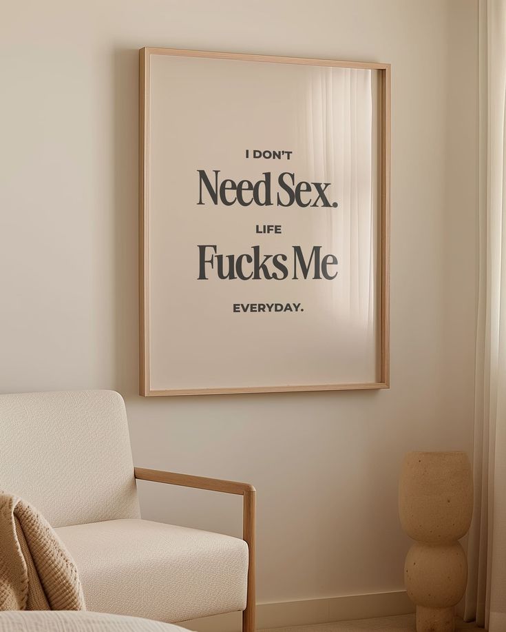 a poster hanging on the wall above a chair in a living room with a window