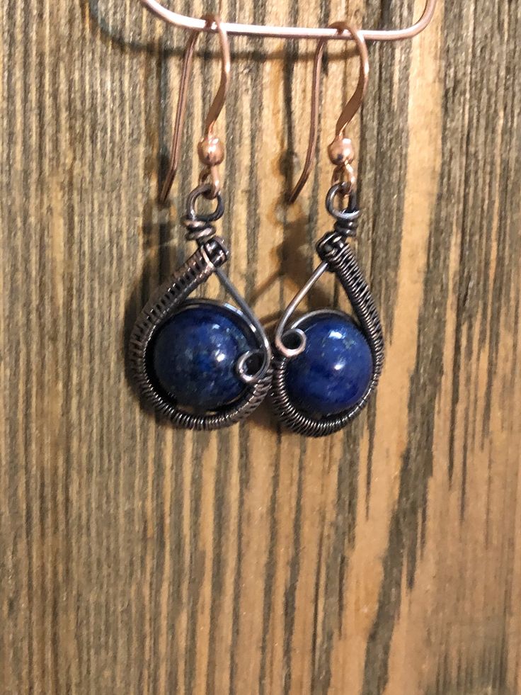 Copper wire has been carefully woven around a 10mm Lapis Lazuli bead to make these cute drop earrings and then suspended from a copper ear wire. The drop is approx. 1 inch in length. These earrings were inspired by Cheryl St. Pierre. Artisan Wire Wrapped Drop Earrings, Blue Wire Wrapped Dangle Earrings, Adjustable Lapis Lazuli Earrings As Gift, Adjustable Lapis Lazuli Earrings For Gift, Blue Lapis Lazuli Teardrop Earrings, Blue Teardrop Lapis Lazuli Earrings, Artisan Blue Nickel-free Earrings, Wire Wrapped Lapis Lazuli Dangle Earrings, Handmade Round Lapis Lazuli Earrings