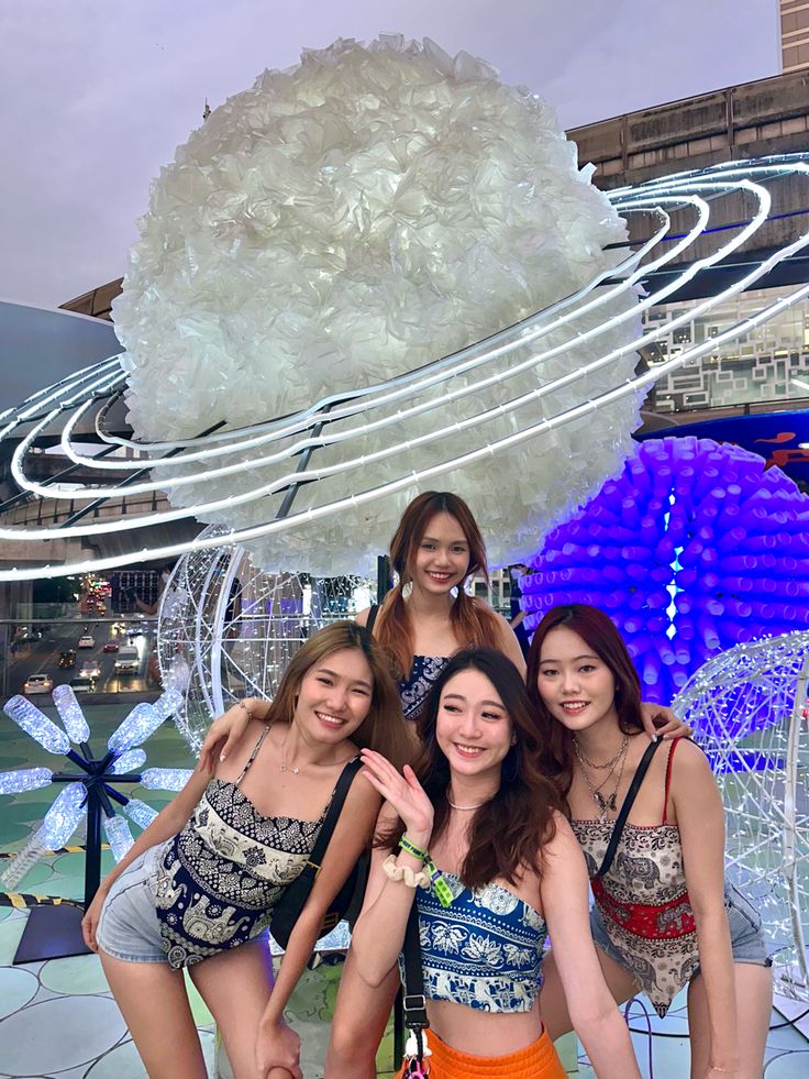 four young women posing for a photo in front of an artistic display