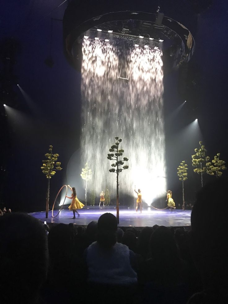 the stage is lit up with bright lights and people in yellow dresses are standing on it