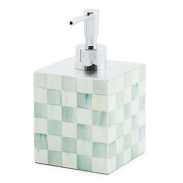 a soap dispenser made out of ceramic tiles with a chrome faucet