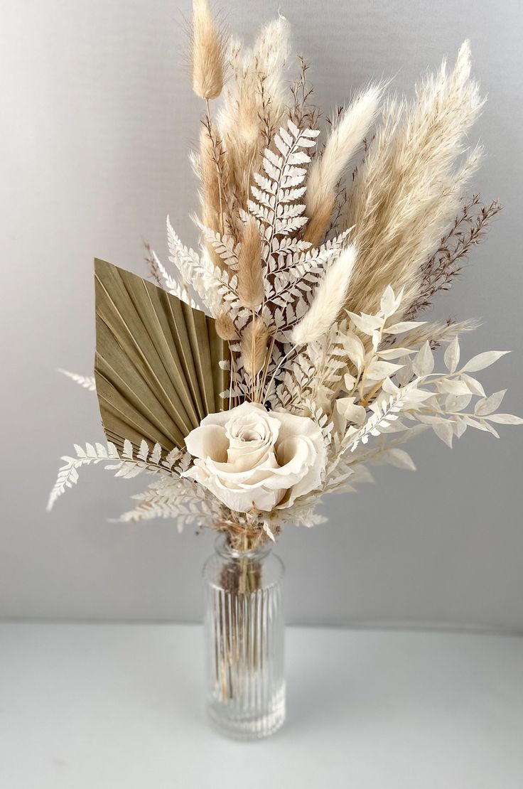 a vase filled with flowers and feathers on top of a table