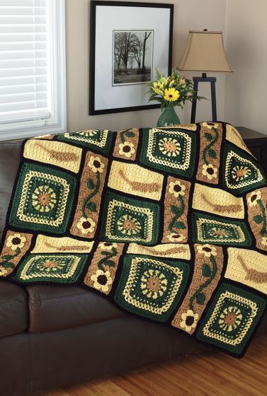 a couch with a green and yellow quilt on it next to a framed photo in a living room