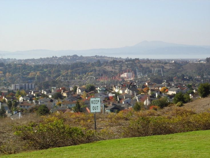 a city with lots of houses and hills in the background, as well as a street sign