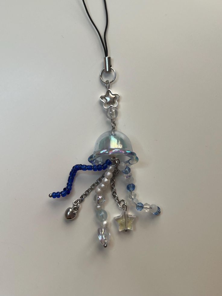 a blue and white beaded necklace hanging from a black cord on a white surface