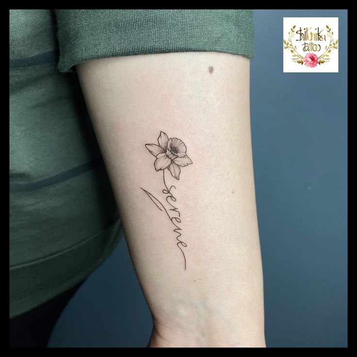 a woman's arm with a small flower tattoo on the left side of her arm