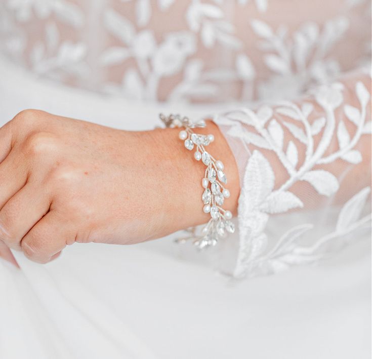 a close up of a person wearing a white dress and bracelet with leaves on it