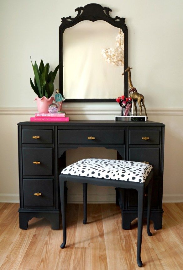 a black desk with a mirror and stool