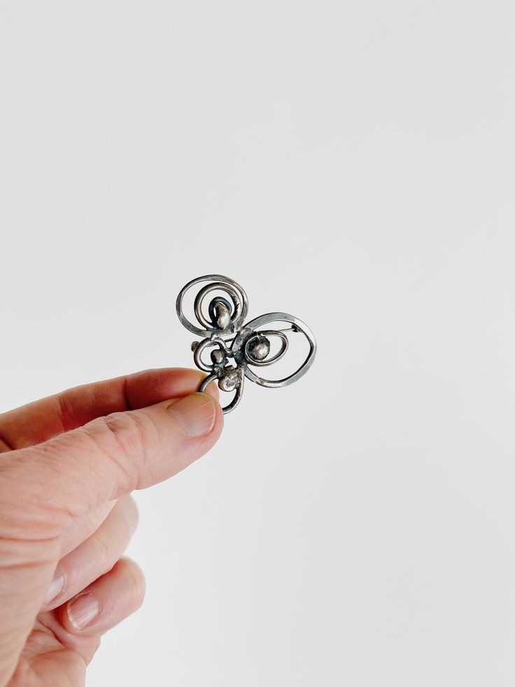 a hand holding a small metal object in it's left hand on a white background