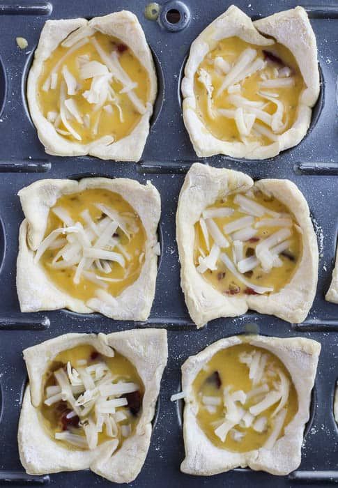 eight mini pizzas with cheese and sauce in them on a baking sheet, ready to go into the oven