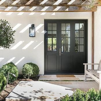 the front door to a house with a bench and potted plant in it's yard