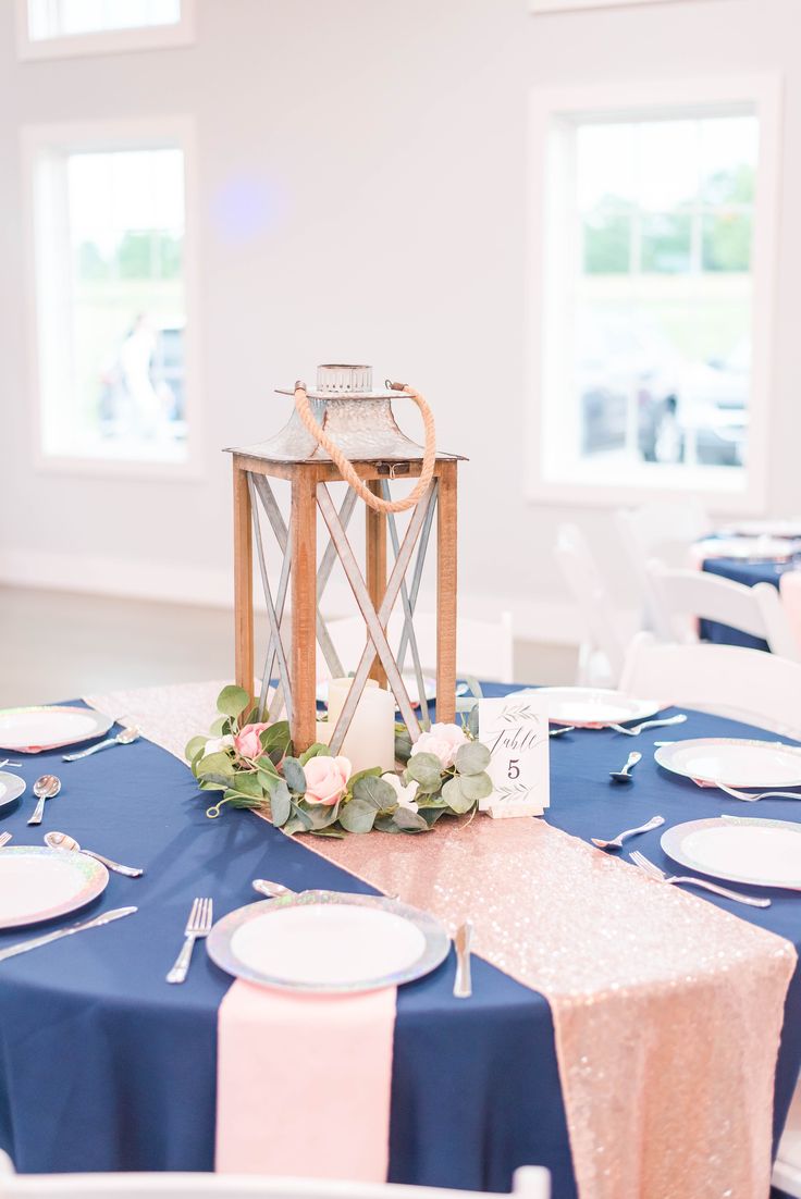 a blue table cloth with pink and white flowers on it is set up for a wedding reception