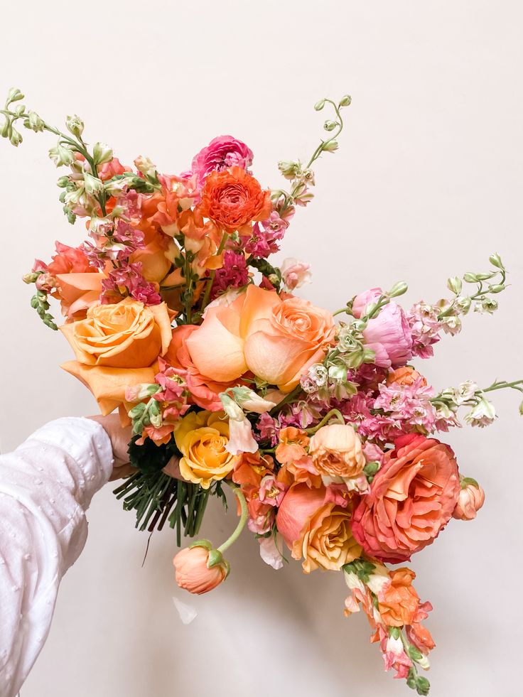 a bouquet of flowers is being held up by someone's hand on a white background